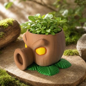Peut inclure: Un pot de fleurs marron et arrondi avec un museau cylindrique saillant et un accent jaune vif en forme d'œil. Le pot présente une surface texturée et repose sur une base en forme de feuilles vertes, contenant une petite plante verte feuillue.