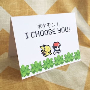May include: A white card with the text "ポケモン! I CHOOSE YOU!" in black. The card features a pixelated image of a trainer and Pikachu.
