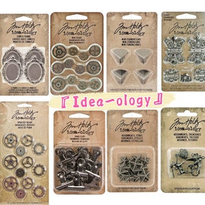 Puede incluir: Surtido de adornos metálicos para manualidades y scrapbooking. El conjunto incluye engranajes, marcos, bisagras, estrellas y otros elementos decorativos. El embalaje presenta la marca "Idea-ology" y una variedad de descripciones de productos.