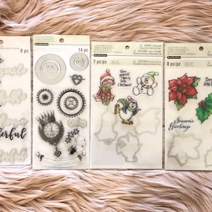 May include: Three clear stamp sets with various designs. The first set has eight stamps with words like "smile", "hello", "love", and "wonderful". The second set has 14 stamps with gears, a clock, and a heart. The third set has seven stamps with a snowman, a penguin, a Christmas elf, and a poinsettia.