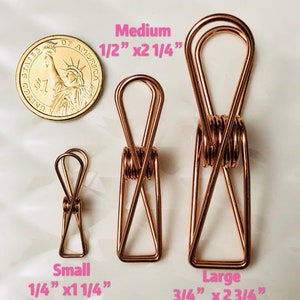 May include: Three gold-toned metal binder clips of different sizes. The smallest clip is 1/4 inch by 1 1/4 inch, the medium clip is 1/2 inch by 2 1/4 inch, and the largest clip is 3/4 inch by 2 3/4 inch.