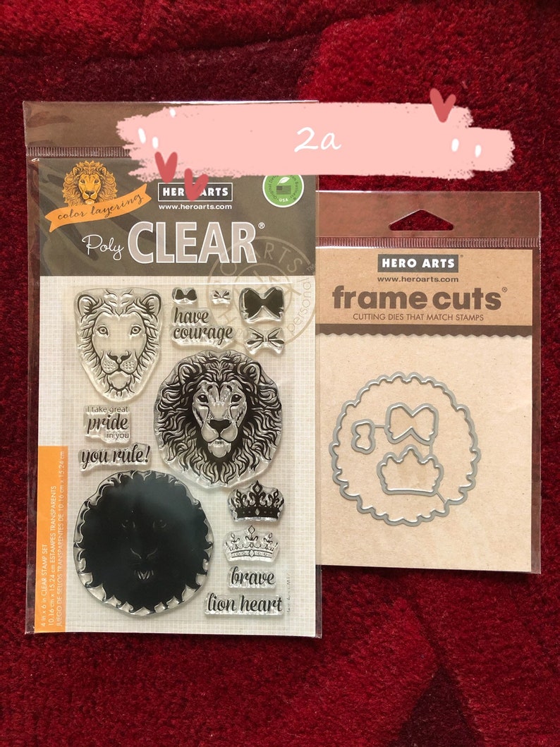 May include: A set of clear polymer stamps and metal cutting dies featuring a lion theme. The stamps include images of a lion's head, a crown, and the words "have courage", "take great pride in you", "you rule", and "brave lion heart". The dies include a circle with a crown and two bows inside.