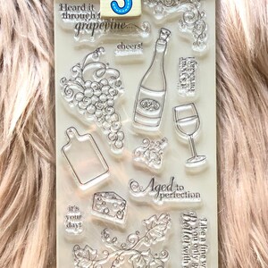 May include: A clear plastic sheet with 10 different rubber stamps for crafting. The stamps feature wine-themed images, including grapes, wine bottles, wine glasses, and the text "Aged to Perfection".