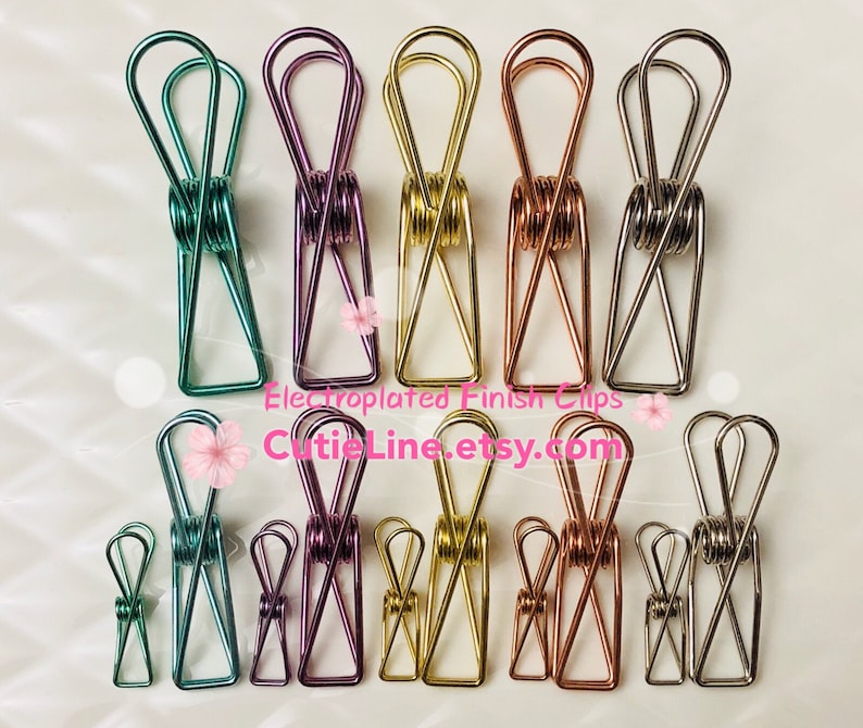 May include: A set of 10 colorful metal binder clips in various sizes. The clips are in shades of green, purple, gold, rose gold, and silver. The clips are electroplated with a shiny finish. The text "Electroplated Finish Clips" and "CutieLine.etsy.com" is visible in the image.