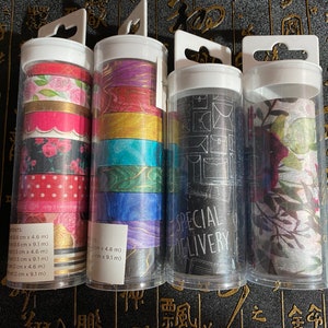 May include: Four clear plastic containers with colorful washi tape rolls. Each container has a different pattern of tape, including floral, geometric, and abstract designs. The containers are labeled with the text "SPECIAL DELIVERY".
