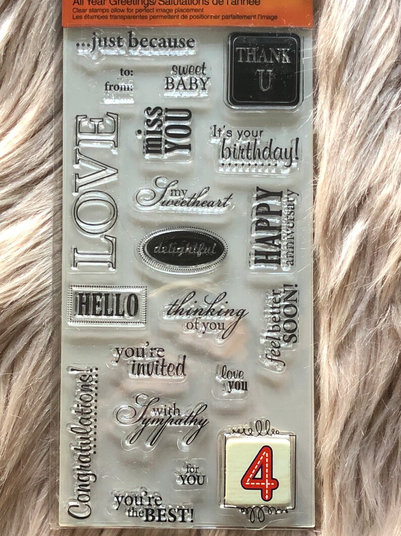 May include: A clear sheet of rubber stamps with various phrases and designs, including "LOVE", "just because", "sweet baby", "thinking of you", "you're invited", "congratulations", "with sympathy", "you're the best", "happy anniversary", "it's your birthday", "thank you", "hello", "feel better soon", and "love you". There is also a number "4" stamp.