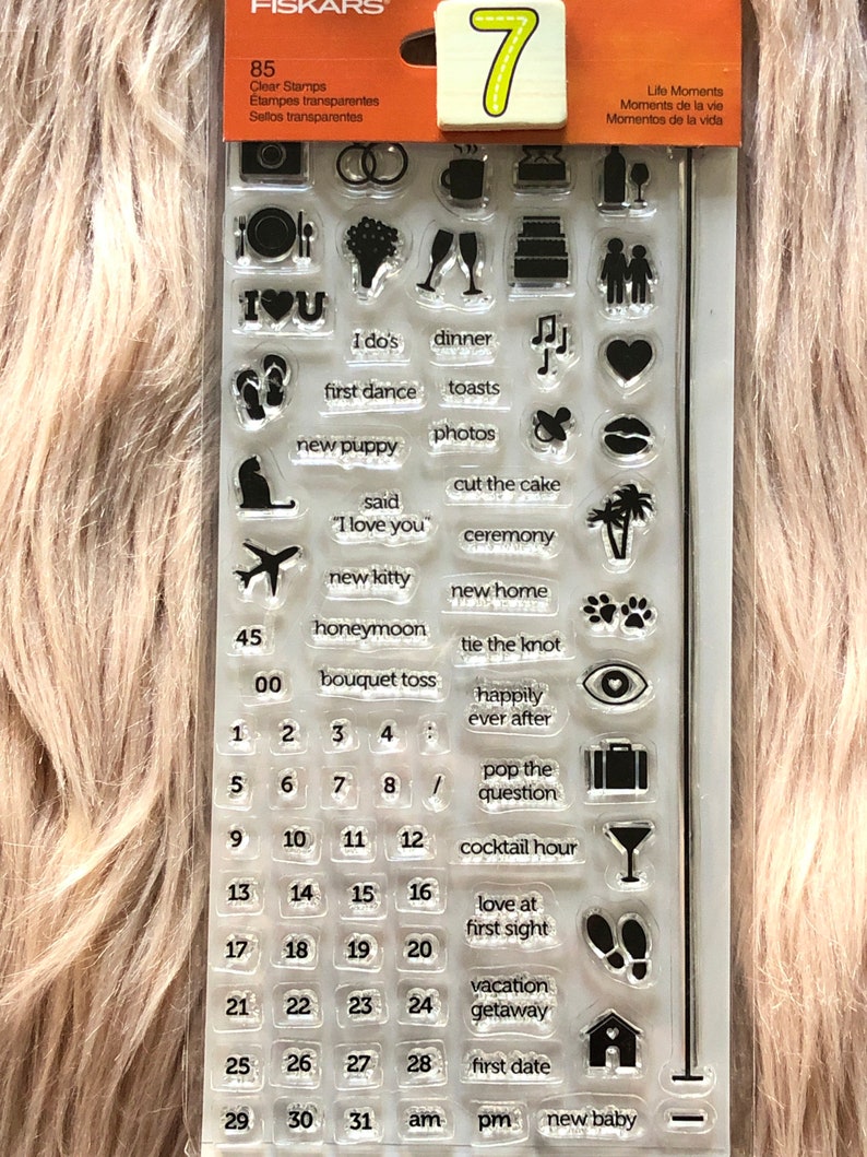 May include: A clear stamp set with 85 different stamps for scrapbooking and card making. The stamps feature various life moments, including "I do's", "first dance", "new puppy", "honeymoon", "happily ever after", "love at first sight", "vacation getaway", "first date", and "new baby".