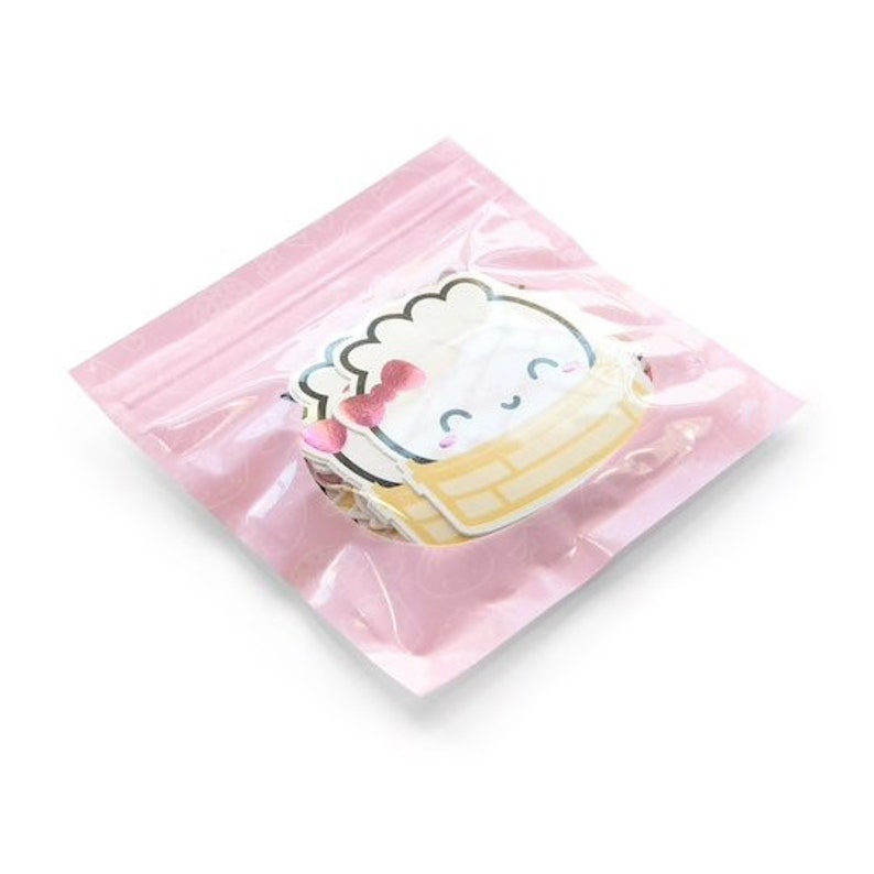 Op de afbeelding: Een roze hersluitbare zak gevuld met witte en gele stickers met een cartoonfiguur met een roze strik. Het figuur zit in een gele mand.