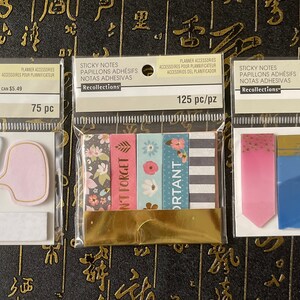 May include: Three packages of sticky notes with different designs. The first package has 75 notes and features a white and light blue dog with a pink speech bubble. The second package has 125 notes and features four colorful patterned sticky notes with the words "Don't Forget" and "Important". The third package has 50 notes and features a pink and blue sticky note with a gold glitter accent.