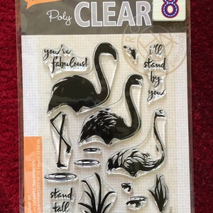 May include: A clear stamp set with 8 stamps featuring flamingo silhouettes, a pond, reeds, and phrases like "you're fabulous!" and "hello gorgeous!" The set is 4 inches by 6 inches (10.16 cm x 15.24 cm).