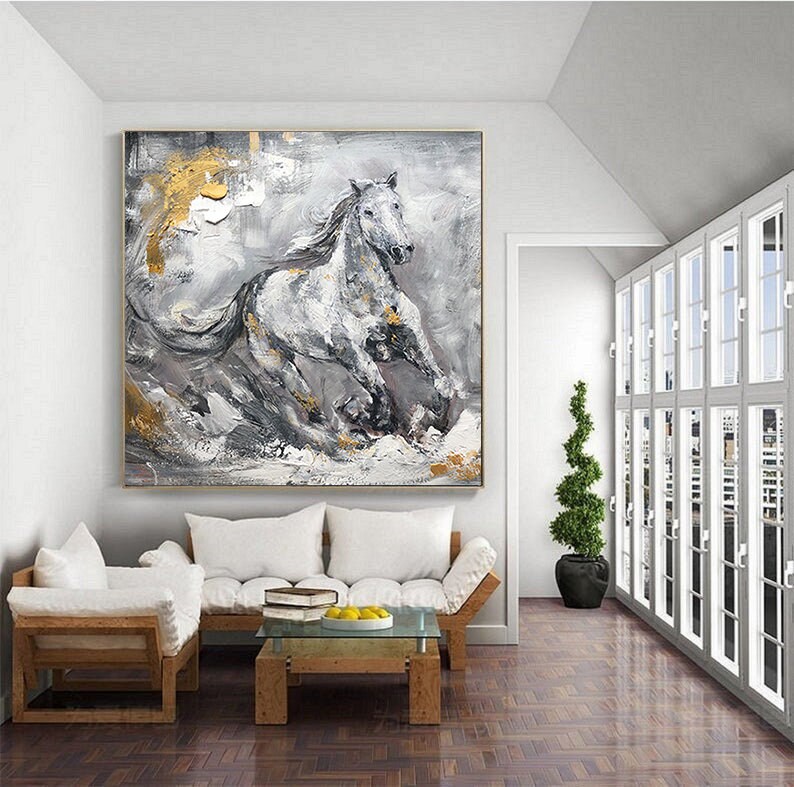 May include: Abstract painting of a white horse running through a grey and gold landscape. The painting is framed and hanging on a white wall.