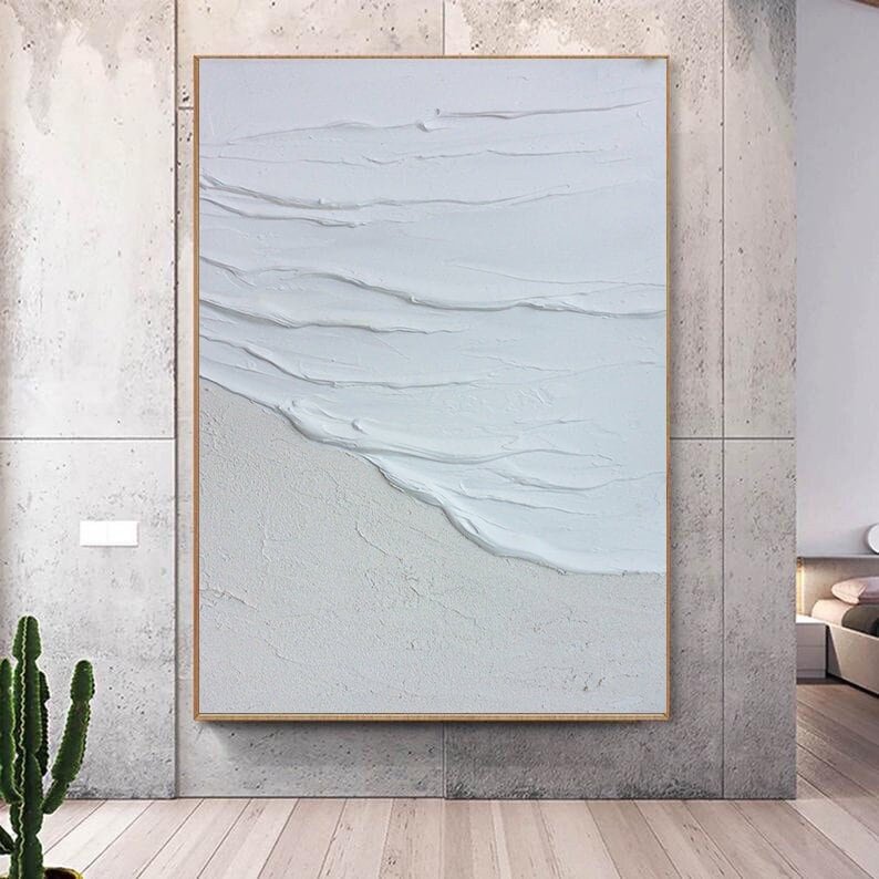 May include: A white abstract painting with textured brushstrokes that resemble waves. The painting is framed in a thin, light wood frame.