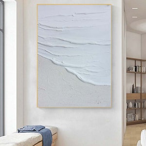 May include: Abstract painting of white waves on a white sandy beach. The painting is framed in a thin gold frame.