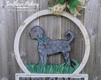 May include: A white wooden welcome sign with a black and white dog silhouette in a circle above the word "WELCOME". The sign is decorated with a green and gold bow.