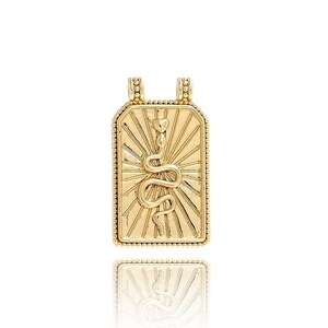 Op de afbeelding: Gouden ketting met hanger, met een rechthoekige bedel met een slangendesign en een zonnestralenpatroon.