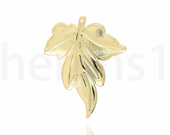May include: A gold leaf pendant charm with a detailed design. The charm is shaped like a leaf with three points and has a textured surface.