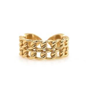 Puede incluir: Un anillo dorado con un diseño de doble cadena. El anillo es de metal y tiene un aspecto grueso y audaz.