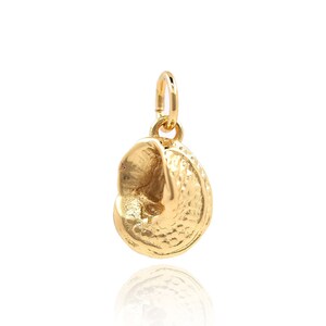 Op de afbeelding: Een gouden schelp hanger. De hanger is gedetailleerd met een getextureerd oppervlak en een licht open vorm.