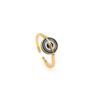 May include: Gold ring with a blue and white evil eye design. The eye has a small clear stone in the center.
