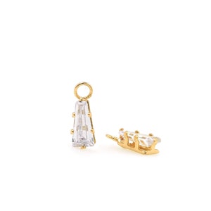 Peut inclure: Deux breloques dorées avec des accents de cristal transparent. Un charme est en forme de larme avec une boucle en haut. L'autre charme est une forme rectangulaire plus petite avec une boucle sur le côté.