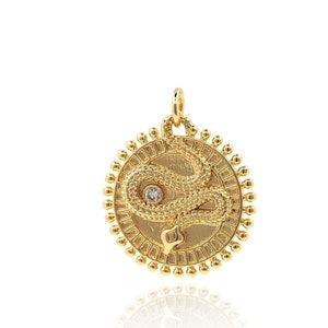 May include: Gold pendant featuring a snake design with a small diamond accent. The pendant is round and has a beaded border.