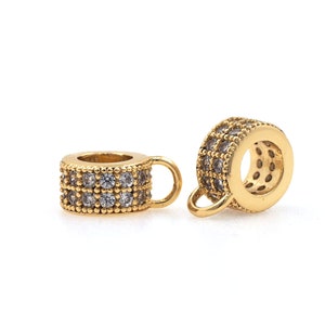 May include: Two gold-toned metal bead spacers with clear crystal accents. Each spacer has a small loop on one side.