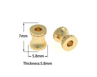 Könnte beinhalten: Zwei goldfarbene Metallperlen mit einer strukturierten Oberfläche. Die Perlen sind 7 mm hoch und 5,8 mm im Durchmesser. Die Perlen werden vor einem weißen Hintergrund gezeigt.