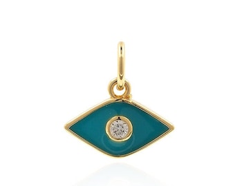 Puede incluir: Un amuleto de oro en forma de ojo turco con esmalte azul turquesa y un diamante transparente en el centro.
