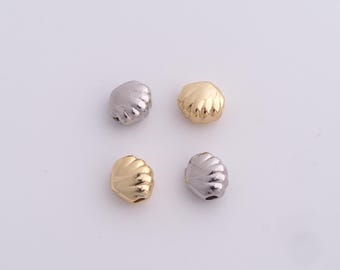 Può includere: Quattro perline a forma di conchiglia, due dorate e due argentate, sono disposte su una superficie bianca. Le perline hanno una texture dettagliata e scanalata e un piccolo foro per l'infilatura. Queste perline decorative sono adatte per la creazione di gioielli.