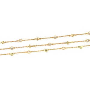 Pode incluir: Três correntes de ouro com diferentes pingentes. A corrente superior tem estrelas, a corrente do meio tem cruzes e a corrente inferior tem corações. Cada corrente tem pedras redondas transparentes.