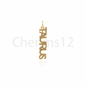 May include: Gold pendant necklace with the word "TAURUS" spelled vertically.
