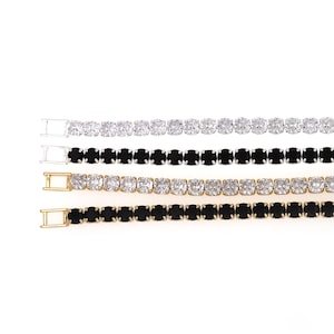 May include: Four gold tone bracelets with a row of clear and black rhinestones. The bracelets have a clasp closure.