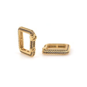 May include: Two gold square-shaped hoop earrings with a pave setting of small clear stones.