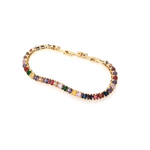 May include: A gold bracelet with a rainbow of square-shaped gemstones.