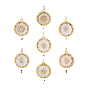 Puede incluir: Siete colgantes de oro con incrustaciones de nácar blanco y detalles de cristal. Cada colgante presenta un diseño diferente: sol, mariposa, corazón, estrella, luna creciente, cruz y estrella.