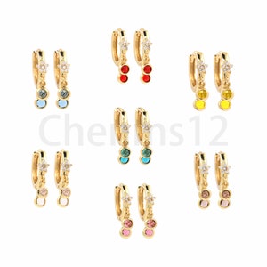 Puede incluir: Conjunto de 10 pares de pendientes de aro dorados con un colgante de estrella y dos pequeñas piedras preciosas de colores. Los pendientes están disponibles en cinco combinaciones de colores diferentes: rojo, azul, amarillo, verde y rosa.