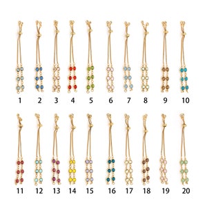 Pode incluir: Vinte pulseiras de corrente dourada com nós deslizantes ajustáveis. Cada pulseira apresenta duas filas de contas de cristal coloridas. As contas são de várias cores, incluindo vermelho, azul, verde, rosa e amarelo.