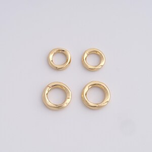 May include: Four gold-colored, circular jewelry components with a textured surface. The components are arranged in a square pattern against a white background. These pieces could be used as beads or charms.