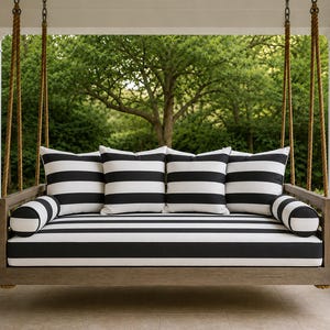 May include: A wooden porch swing suspended by thick ropes, featuring a rectangular seat cushion and four square back cushions, all upholstered in a bold black and white horizontal striped fabric, complemented by two matching cylindrical bolster pillows.