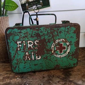 Estuche metálico con paquetes de botiquín de primeros auxilios de la Cruz Roja Americana de la década de 1950