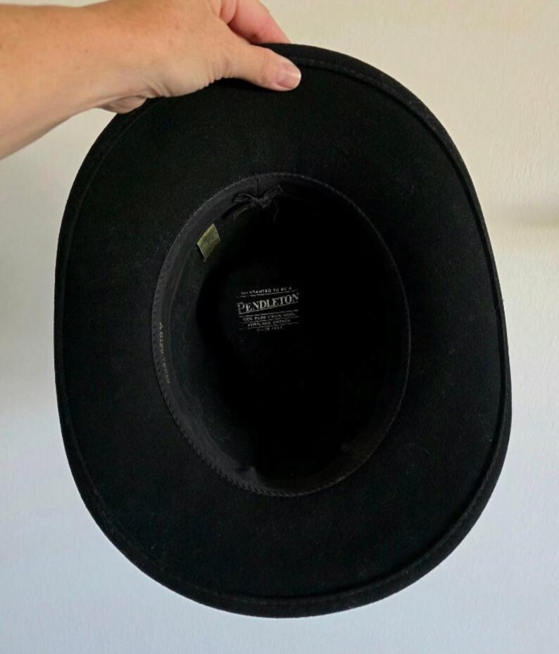 Pu&ograve; includere: Un cappello in feltro nero con tesa larga e corona strutturata. L'interno presenta una fascia tergisudore in tessuto nero e un'etichetta bianca stampata con il testo Pendleton, 100% pure virgin wool, Portland, Oregon, made in USA, all'interno.