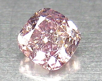 May include: A cushion-cut pink diamond with a light pink hue and a slightly cloudy appearance.