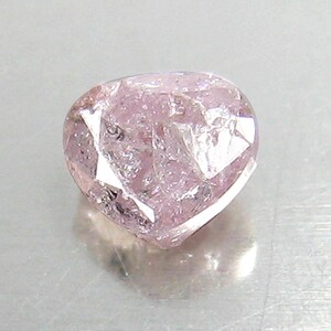 May include: A heart-shaped pink diamond with a rough, faceted surface.