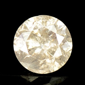 May include: A round, clear, faceted gemstone with a light yellow hue. The gemstone is set against a black background.