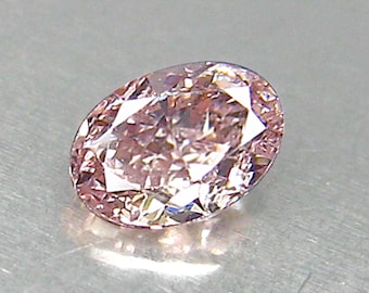 May include: A light pink oval-shaped diamond gemstone with a faceted cut.
