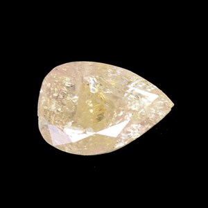 May include: A pear-shaped, light yellow gemstone with a faceted cut. The gemstone has a slightly pink hue and is translucent.