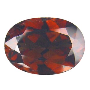 May include: An oval-shaped, faceted gemstone with a deep red and brown color. The gem has a polished surface with multiple facets that reflect light, creating a sparkling effect. The gemstone is set against a white background.