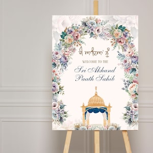 May include: A white sign with a floral wreath border in shades of pink, blue, and green. The sign says "Welcome to the Sri Akhand Paath Sahib" in gold lettering. The sign also features a watercolor illustration of a golden dome structure with a blue canopy.