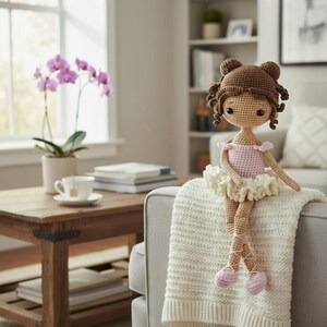 Puede incluir: Mu&ntilde;eca de bailarina de ganchillo hecha a mano, con cabello casta&ntilde;o peinado en mo&ntilde;os y rizos. Lleva un maillot rosa y un tut&uacute; crema, con zapatillas de ballet rosas. La mu&ntilde;eca est&aacute; sentada sobre una manta de punto color crema.