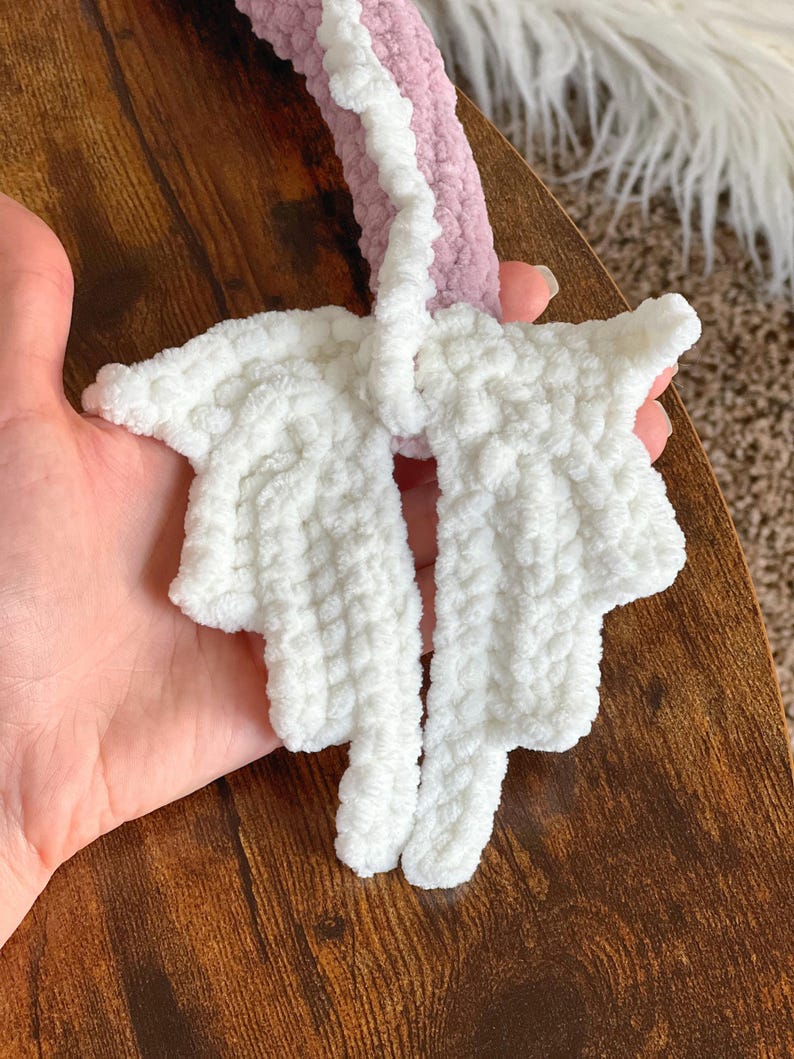 May include: A white crocheted unicorn horn with a pink crocheted base. The horn is made of soft, fluffy yarn and has a pointed tip.